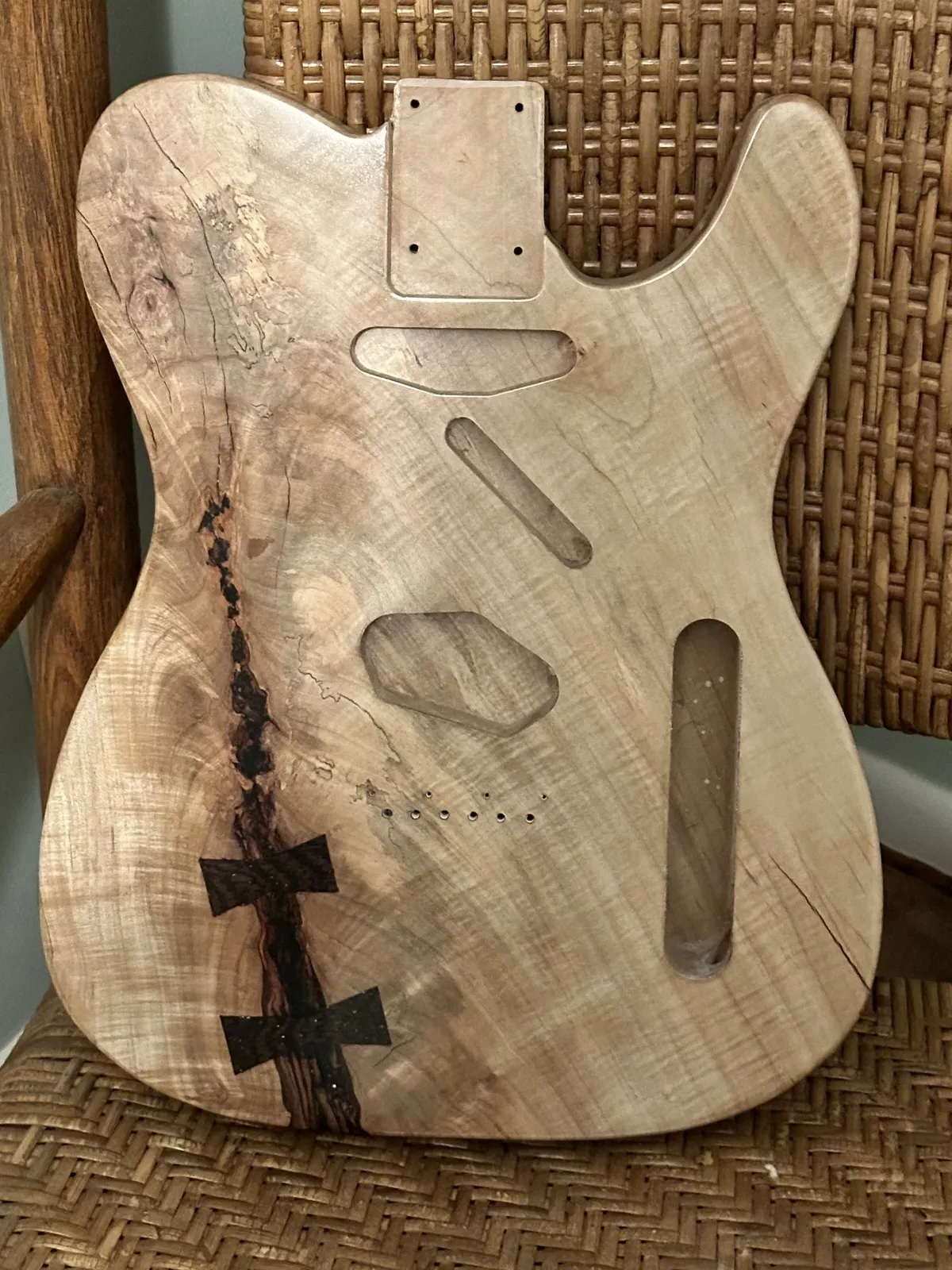 Unfinished guitar body with routed cavities and a butterfly key inlay