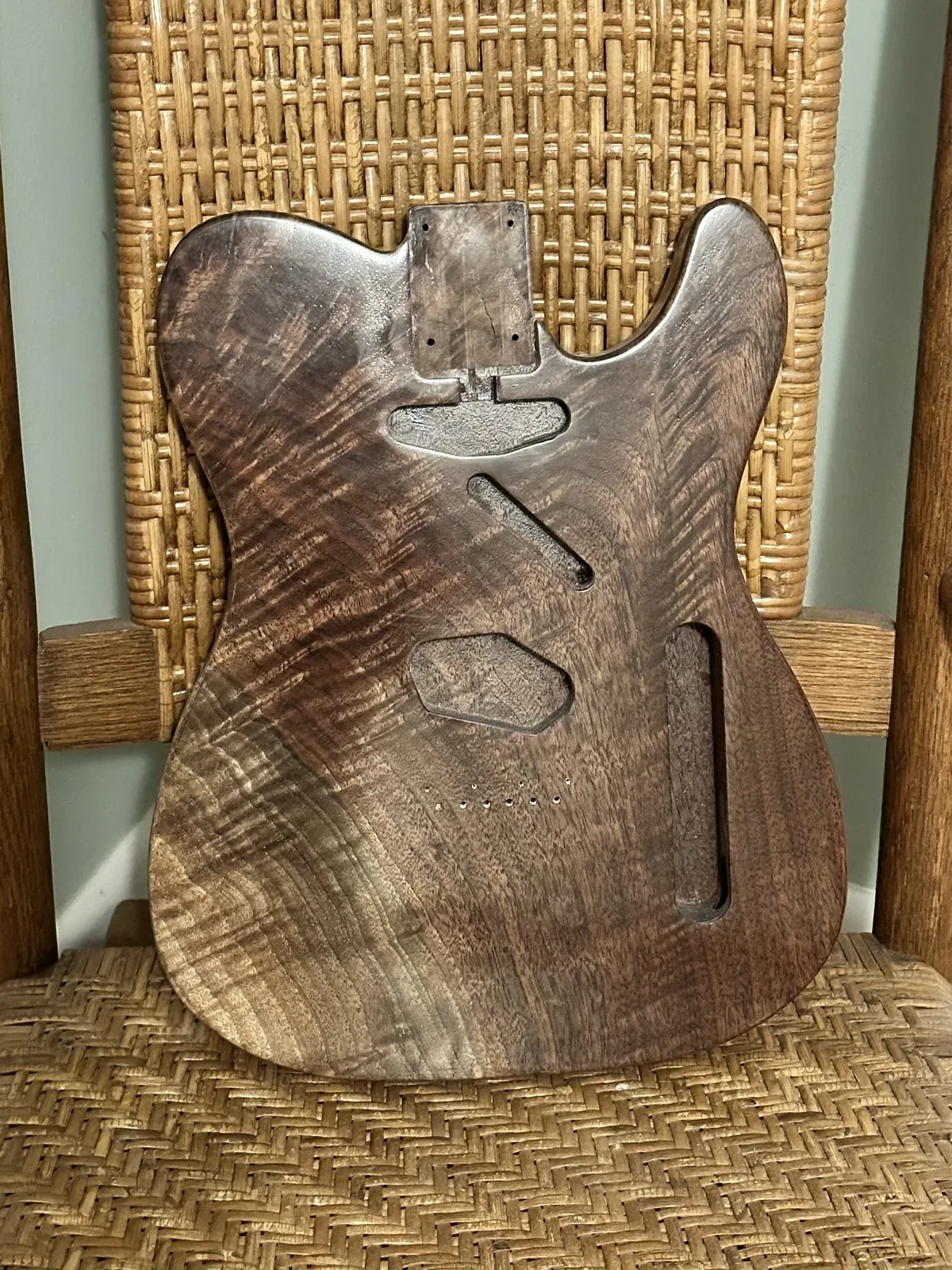 Front of a stained walnut guitar body with routed cavities