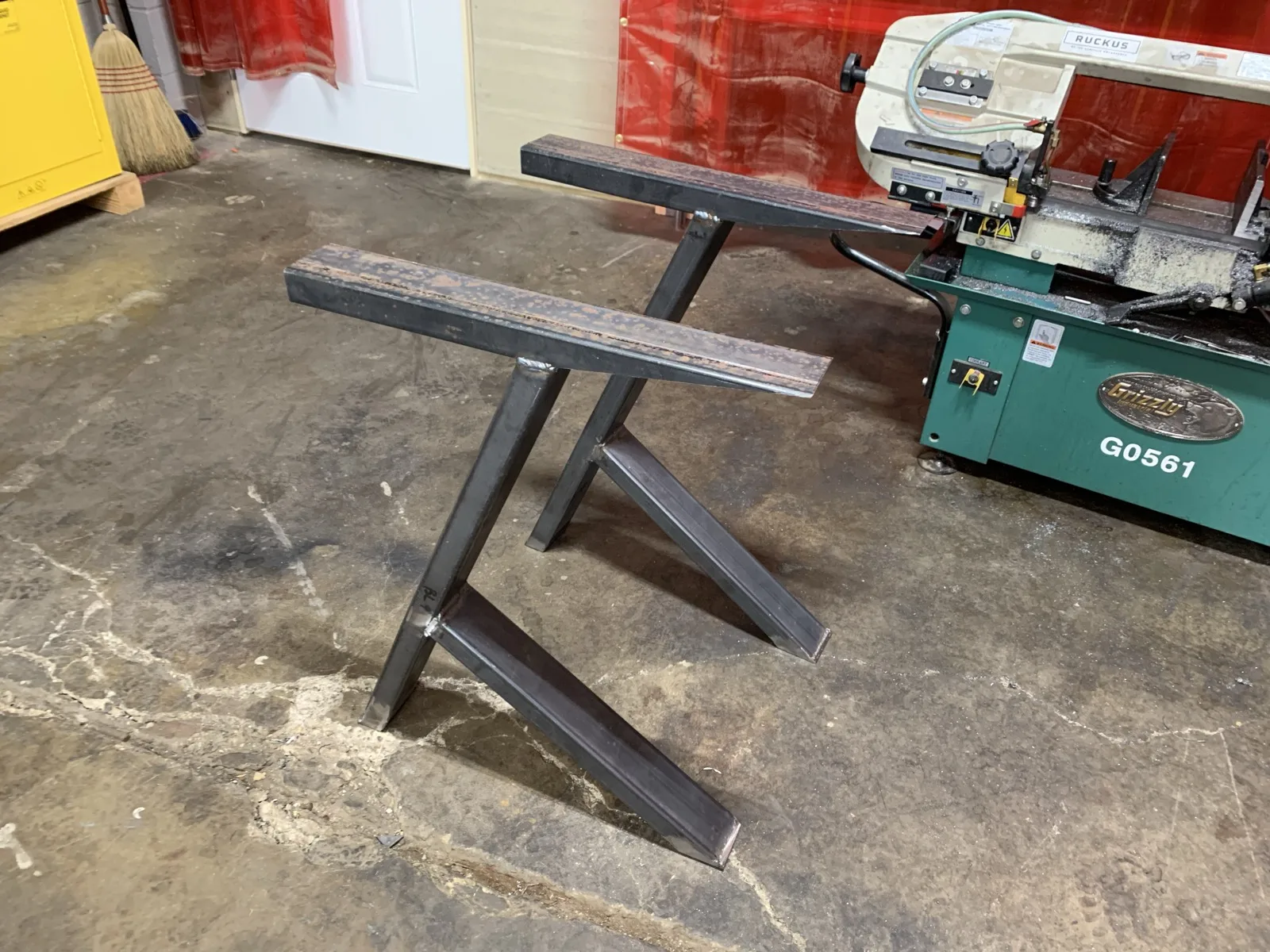 Two powder-coated steel table legs standing in a shop
