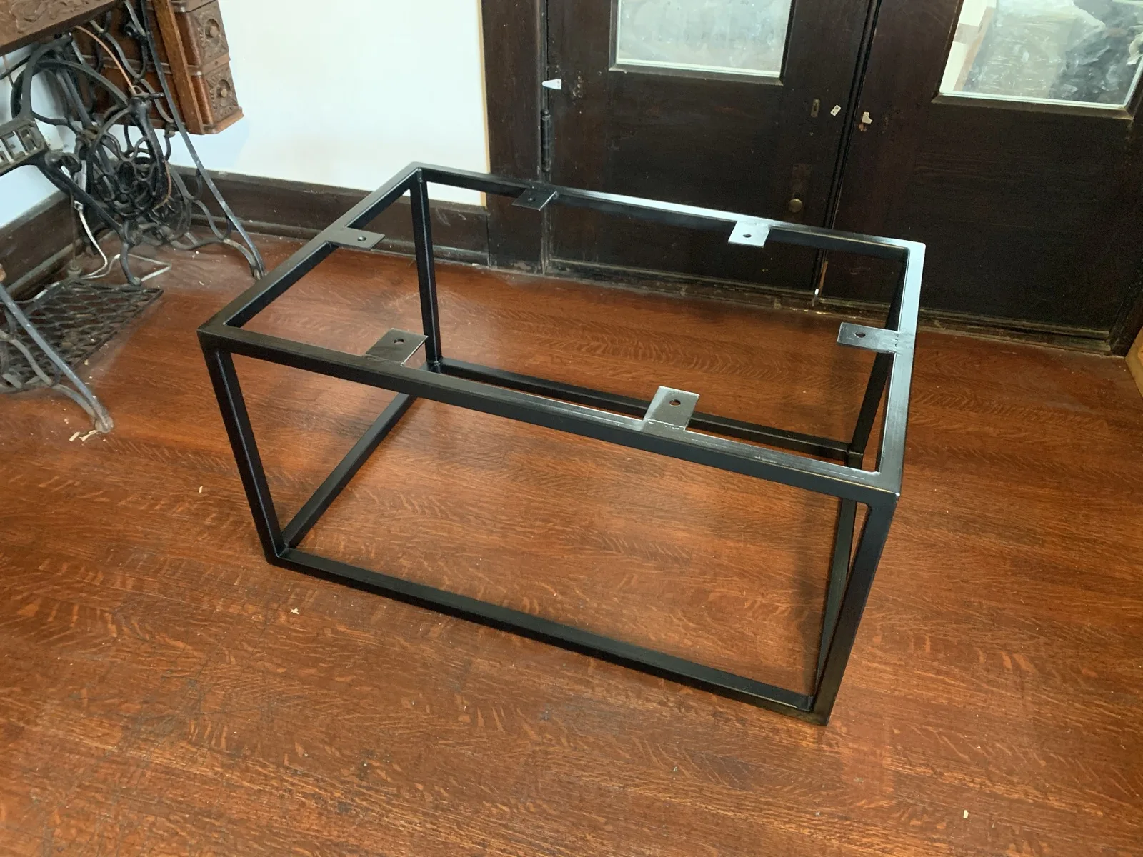 Finished black steel table frame on a hardwood floor