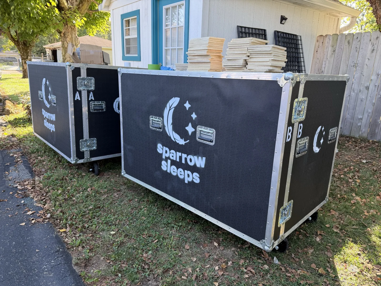 Sparrow Sleeps branded road cases with stacked wood boards