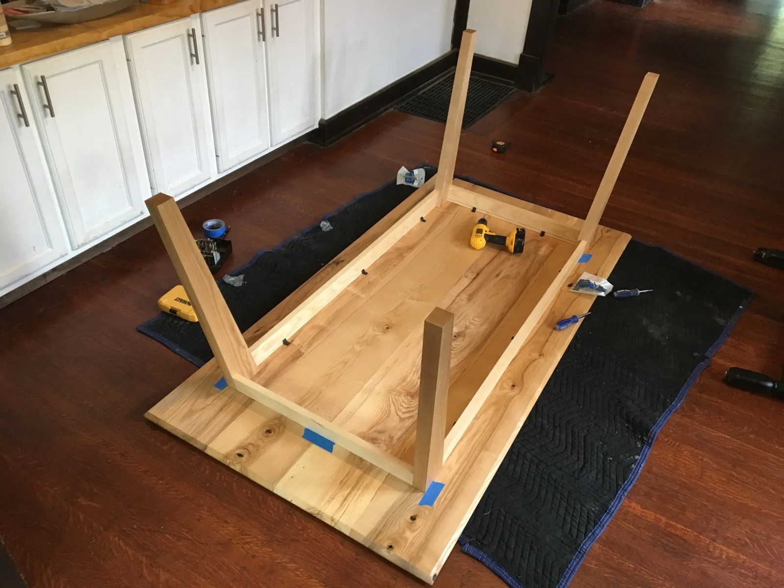 Dining table frame assembly with legs clamped in a kitchen